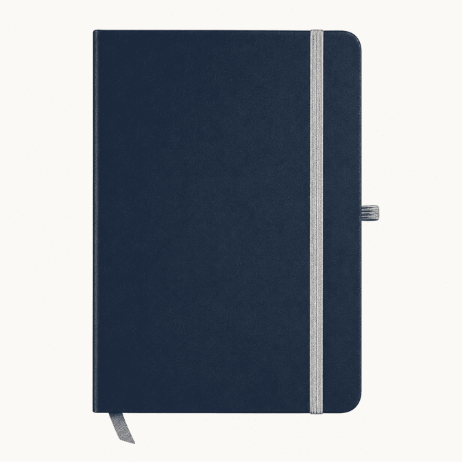 A navy blue A5 notebook with a grey elastic band and a ribbon bookmark. It features a logo on the cover.