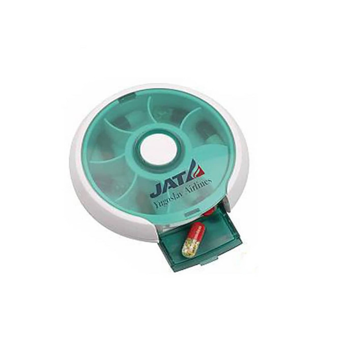 A round, turquoise and white pill box with compartments for seven days and a slide-out drawer. It features a logo.