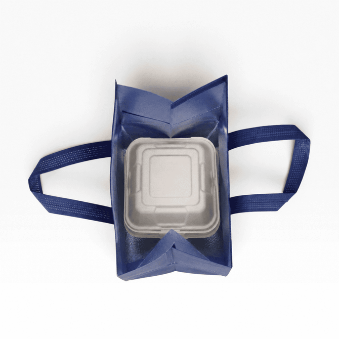 A navy insulated reusable bag with two handles, containing a square white food container inside. It has a logo on the exterior.