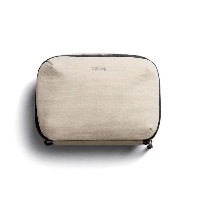 A beige tech kit with a zip closure and a logo on the front, featuring a textured fabric design.