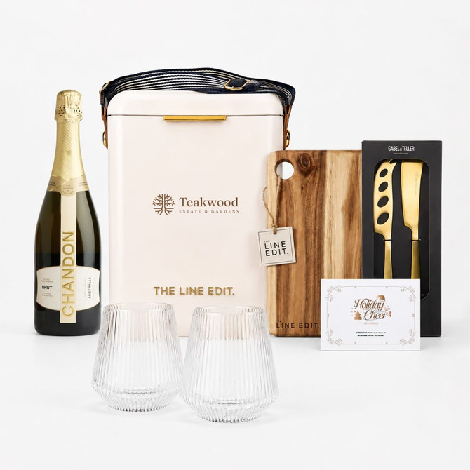 A champagne bottle, wine glasses, a cutting board, utensils, and a branded cooler in beige and natural wood tones.