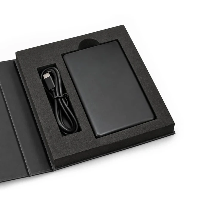 A black solid-state power bank with a USB cable, displayed in a black presentation box.