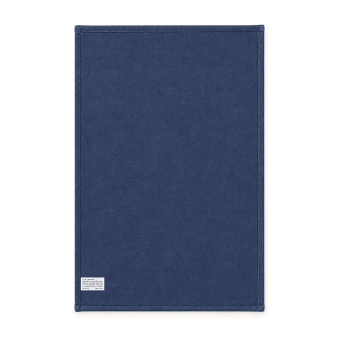 A medium cotton tea towel in navy blue with stitched edges and a small tag. It has a simple design and a logo.
