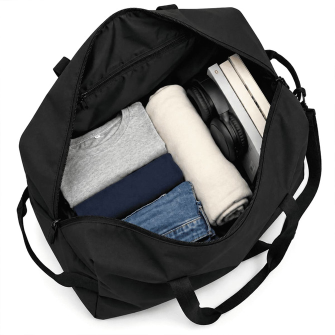 A black duffel bag with neatly packed clothing, headphones, and a book, showcasing its spacious interior.