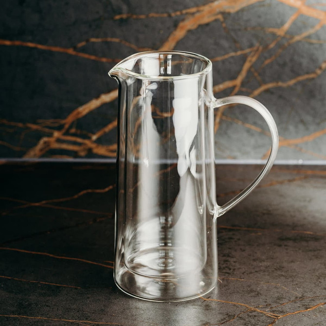 A drink jug made of clear glass with a curved handle and spout, featuring a sleek, modern design.