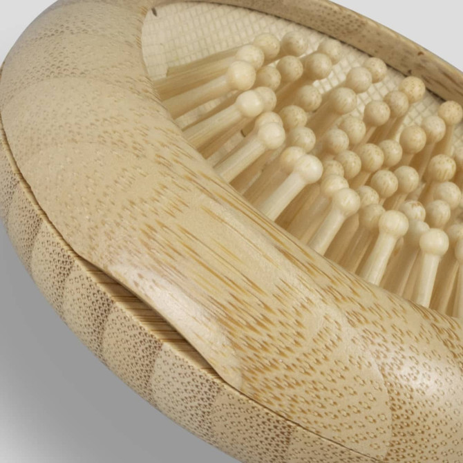 A bamboo brush with wooden bristles, featuring a textured handle, showcasing its natural finish.