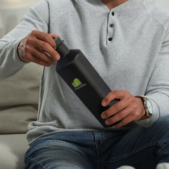 A drink bottle in matte black held by a person wearing a grey top, featuring a logo on the front.