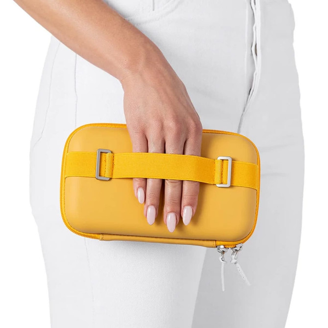 A bright yellow mini bag held in a hand, featuring a strap and a smooth exterior. The background shows white clothing.
