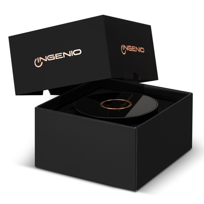 A wireless charging speaker in a sleek black box, featuring a logo on the packaging. The speaker surface is glossy and black.