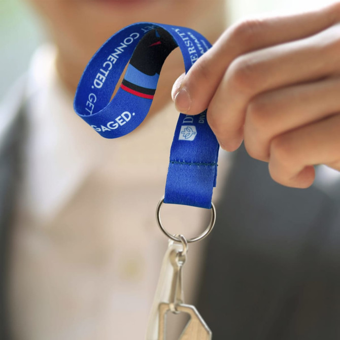 A key ring with a blue ribbon attached, featuring a silver keychain and branding on the ribbon.