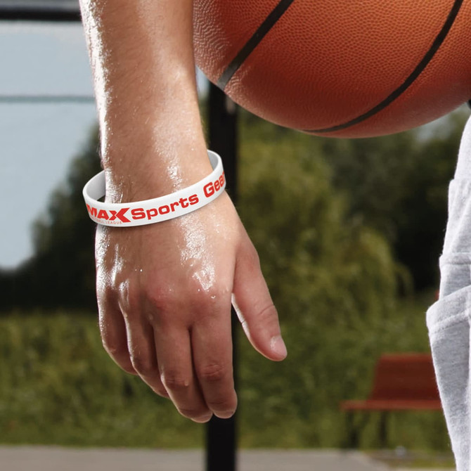 A white silicone wristband with a logo, worn on a hand holding a basketball.