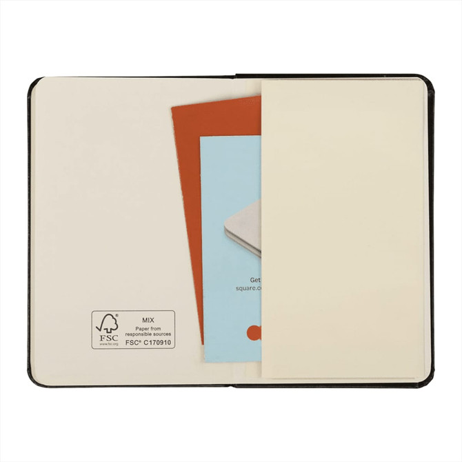 A black bound journal with an open cover revealing blank pages, a small card, and an information sheet inside.