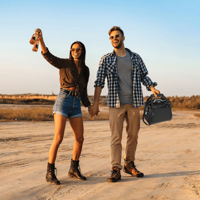 A couple holding hands outdoors, with one carrying a black lunch cooler. The scene is set against a sunset backdrop.