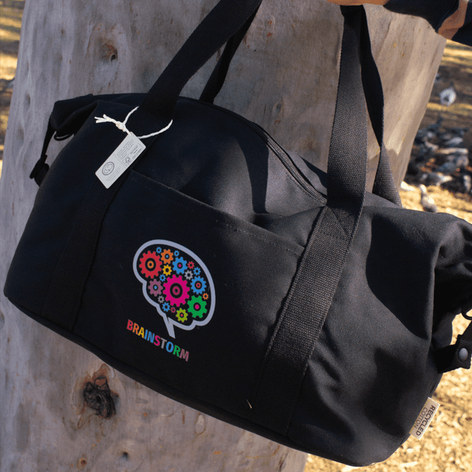 A black duffle bag with a colourful logo and two sturdy handles, featuring a recycled canvas material.