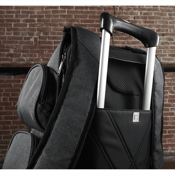 A black and grey compu-backpack featuring a retractable handle and a side pocket, set against a brick background.