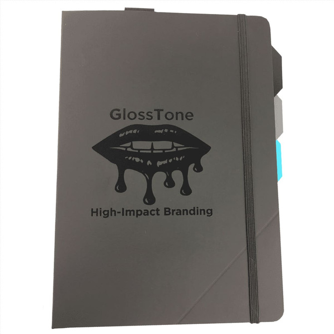 A black notebook with an elastic band closure and a logo featuring dripping lips, accented with colour tabs.