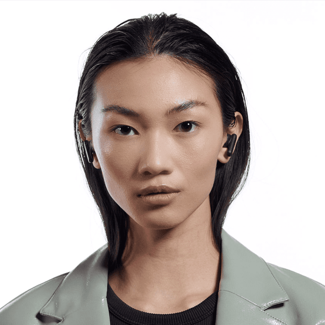 A pair of black Skullcandy Smokin' Buds earbuds worn by a model with long, straight hair, set against a white background.