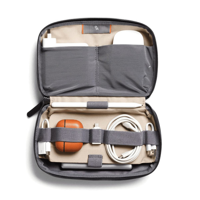 A grey tech kit containing charging cables, an Apple Pencil, and a brown AirPods case, with an interior pocket.