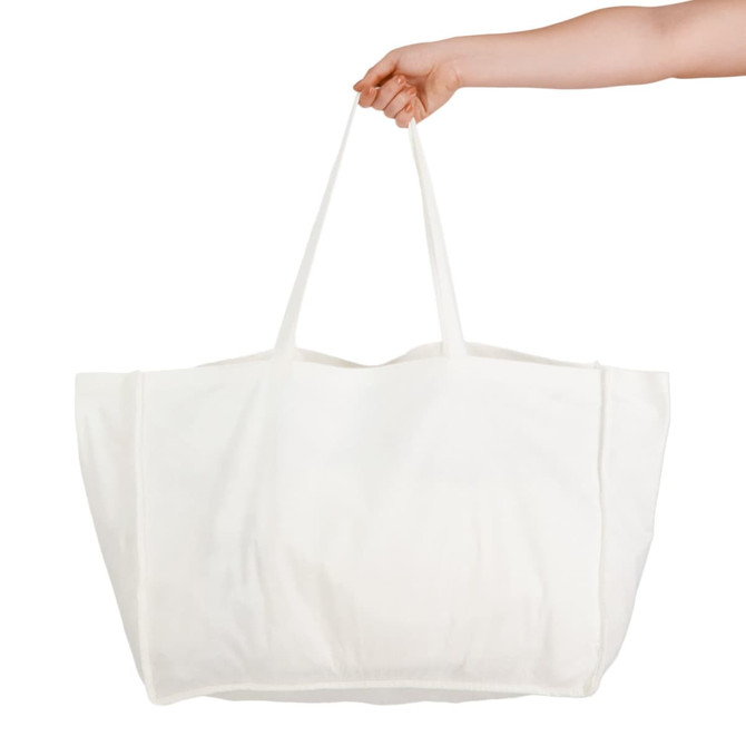 A hand holds a large, white reusable grocery bag with two sturdy straps. The bag has a plain design and no visible branding.