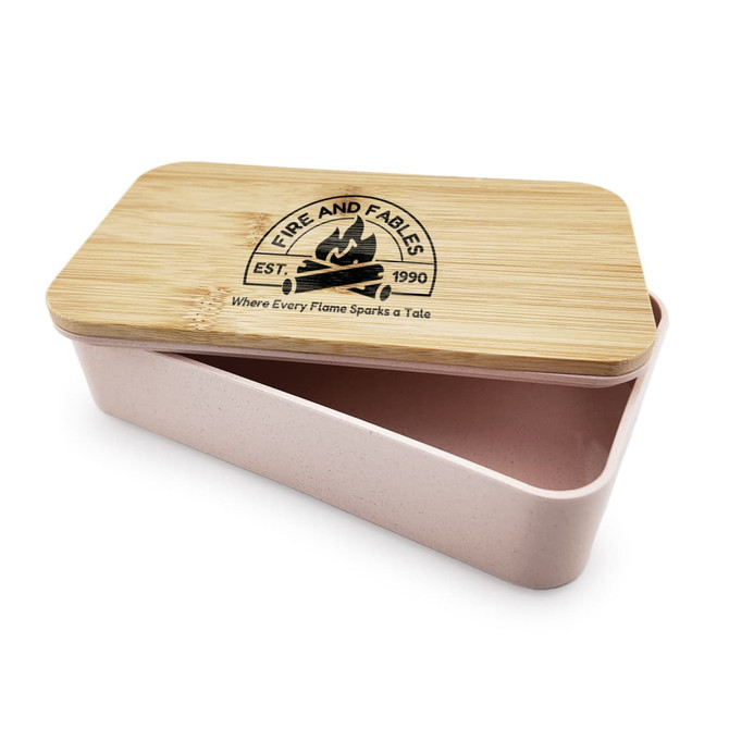 A pink lunch box with a bamboo lid and a logo on top, featuring a two-compartment design.
