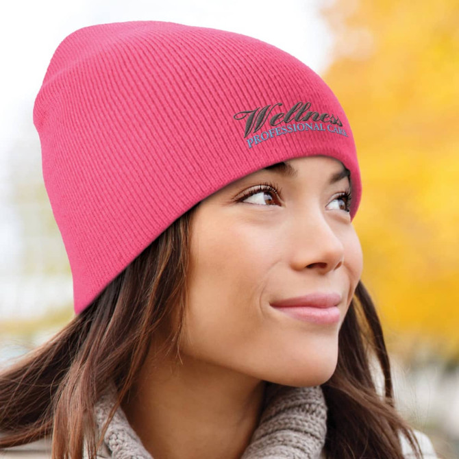 A pink knitted beanie featuring the logo "Wellness Professional Care."