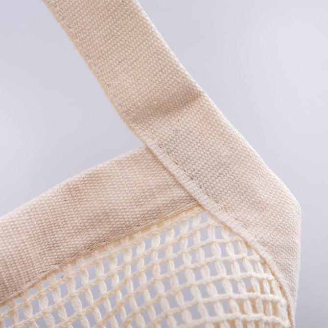 A beige mesh tote bag featuring strong fabric straps and a textured design. It includes a logo on one side.