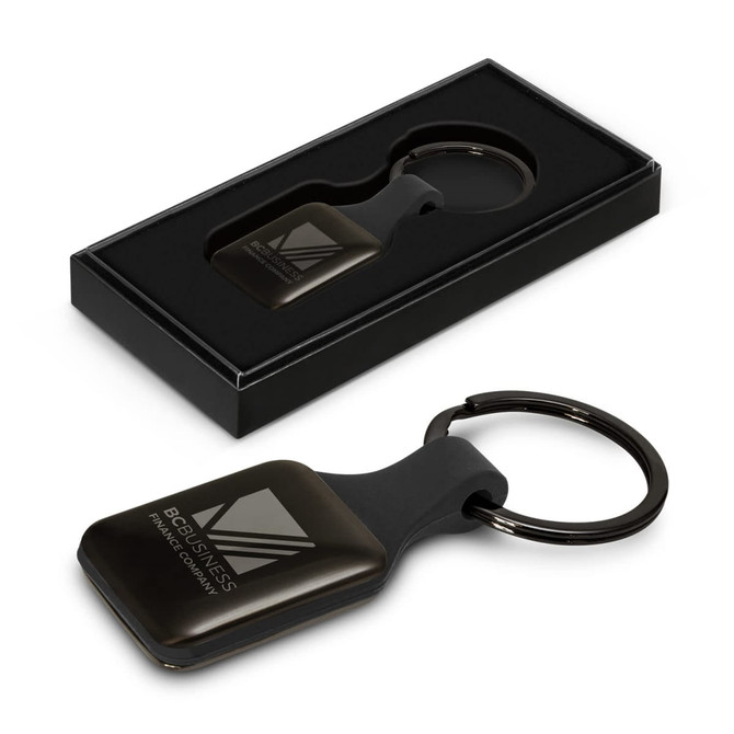 A square black key ring with a smooth finish, presented in a sleek black box, featuring a logo.