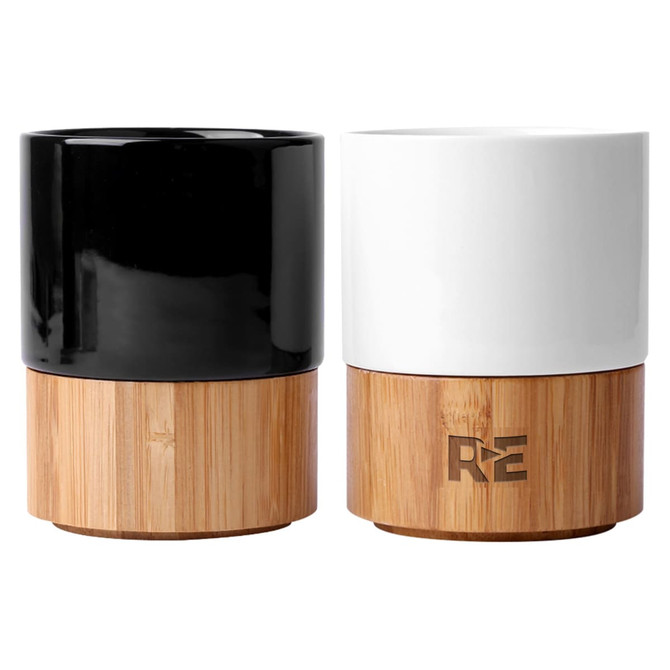 A set of two ceramic mugs, one black and one white, with bamboo bases and a logo on the side.
