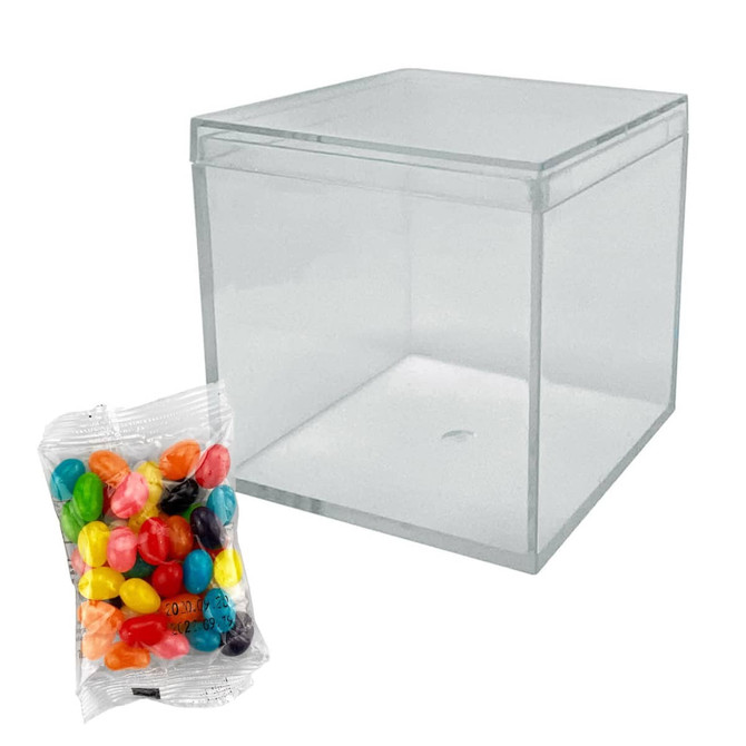 A clear cube container with a pack of rainbow-coloured jelly beans in front.
