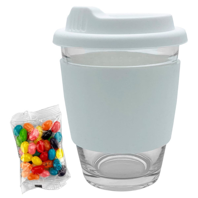 A clear Carlo glass coffee cup with a light blue silicone lid and sleeve, alongside a pack of colourful jelly beans.