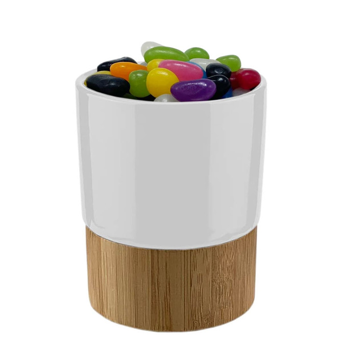 A ceramic mug with a wooden base filled with colourful jelly beans in various shades.