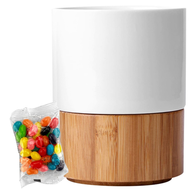 A white ceramic mug with a bamboo base, accompanied by a pack of colourful jelly beans.