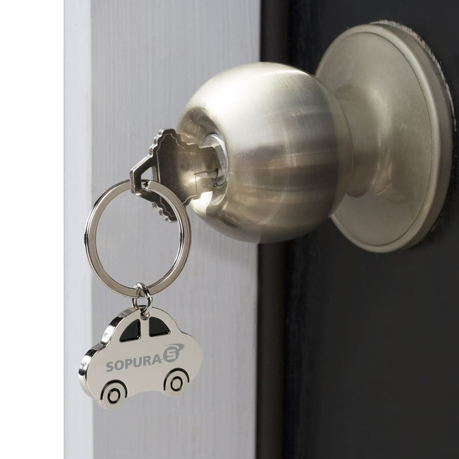 A silver car-shaped key ring hanging from a doorknob, featuring a logo on its side.