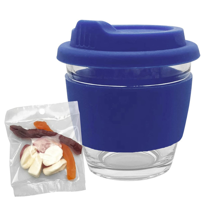 A clear glass coffee cup with a blue silicone lid and sleeve, accompanied by mixed lollies in a transparent bag.