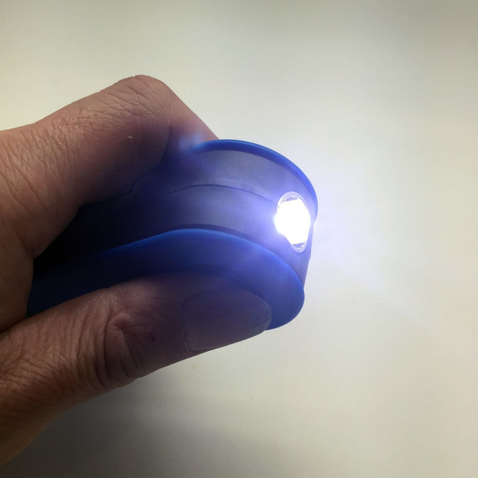 A blue 360 Degree Torch held in a hand, emitting a bright light from its front.