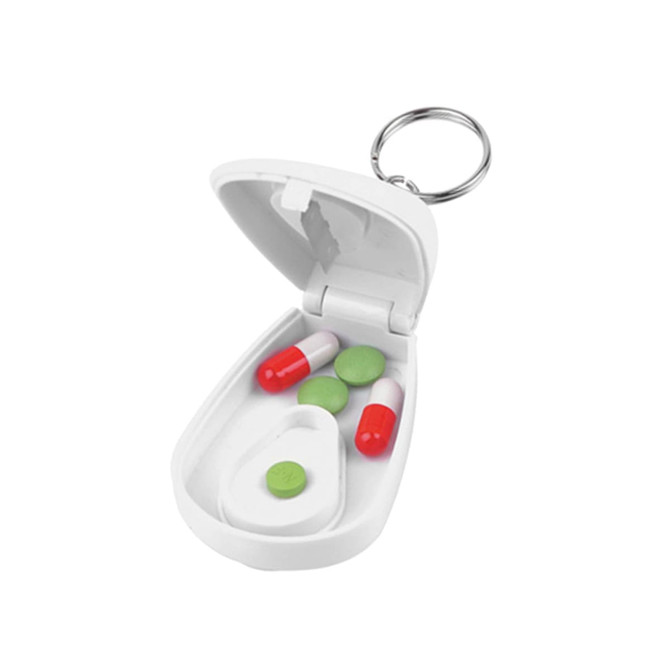 A white pill cutter with a keychain, containing red and green capsules inside.