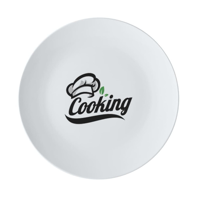 A white coupe dinner plate with a black logo featuring a chef's hat and the word "Cooking."