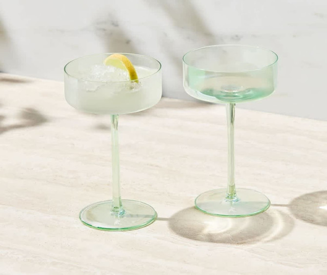 A set of two glass coupe cocktail glasses in a soft green hue, presented in a gift box.