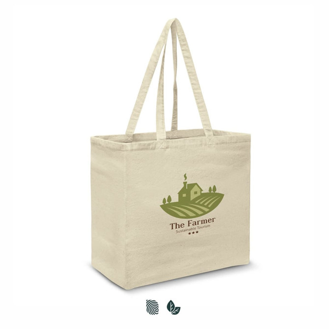 A cream cotton tote bag with sturdy handles and a logo depicting a farmhouse and fields.