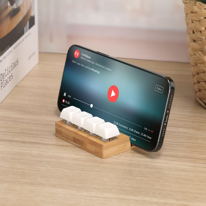 A bamboo stand with white keyboard-shaped stress relievers and a smartphone resting on it.
