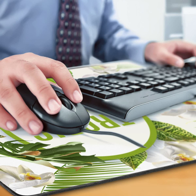A hand using a black mouse on a floral-printed desk mat, with a keyboard visible in the background.