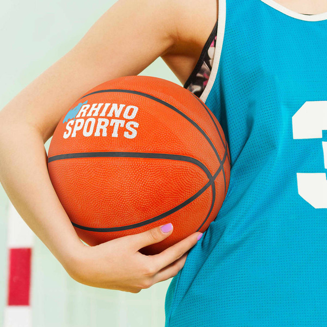 A basketball held by a person wearing a teal sports jersey, featuring a logo and a number. The ball is orange.