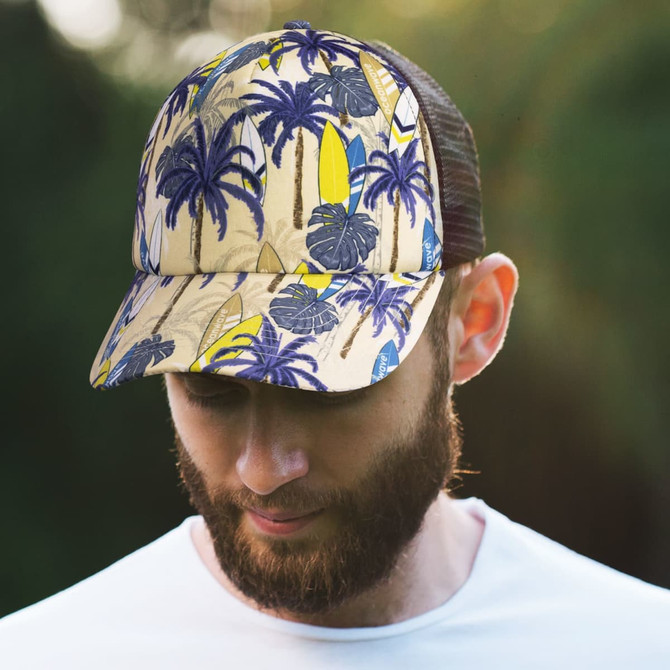 A cap featuring a tropical palm tree and surfboard design, predominantly in yellow and blue, with a mesh back.