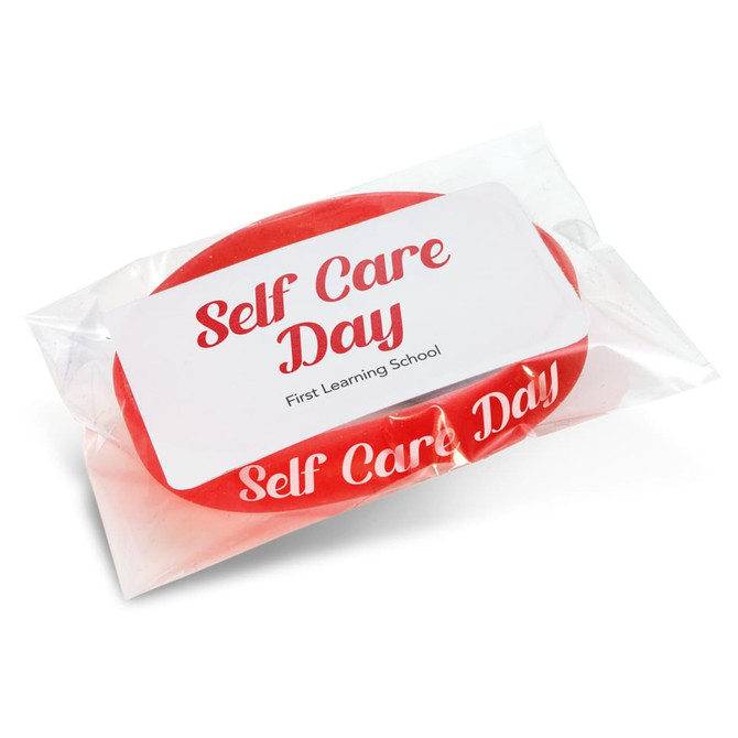 A red silicone wristband packaged in plastic, featuring a label with the words "Self Care Day" and a logo.