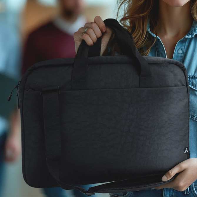 A black laptop bag with handles and a shoulder strap, held by a person in casual attire.