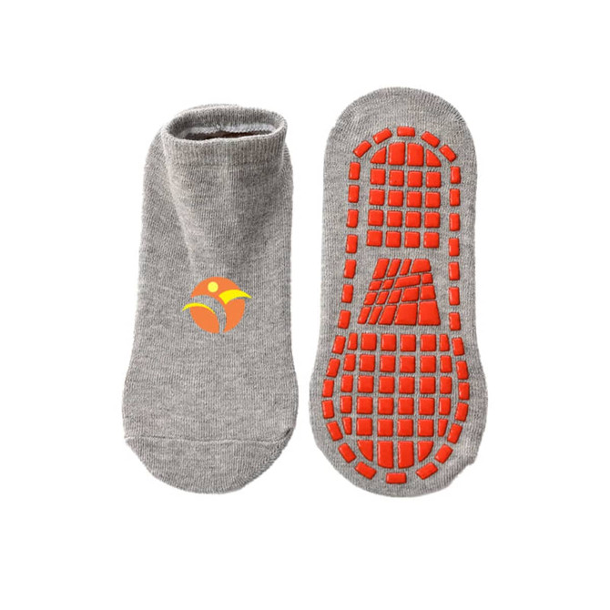 Low cut grey gripper socks featuring a textured orange bottom and a small logo.