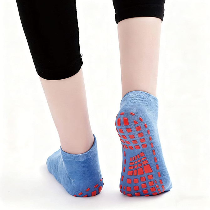 Low cut kids' socks in blue with red gripper soles, featuring a textured bottom for enhanced grip.