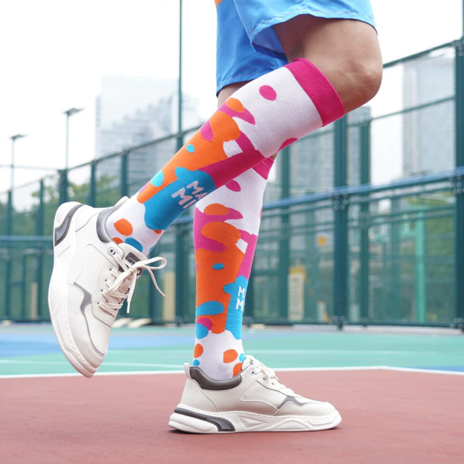 Knee high socks featuring a vibrant pattern of pink, blue, and white, paired with sporty footwear.