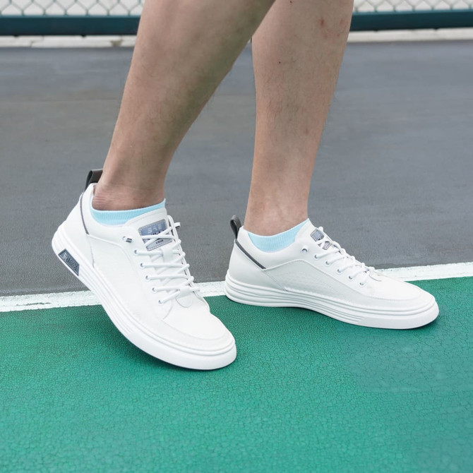 White low cut socks paired with white sneakers on a green court surface. The socks feature a light blue accent.