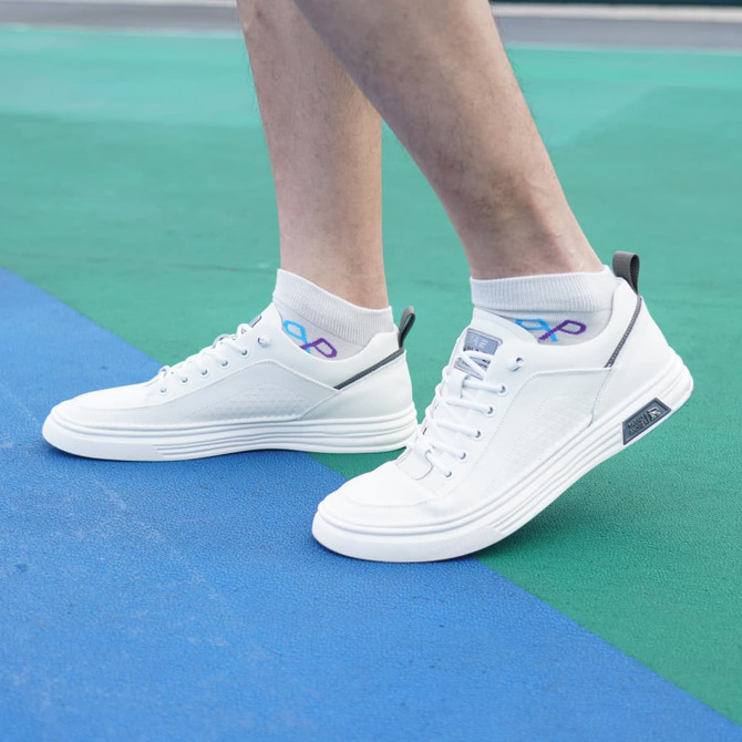 White ankle socks with a towel bottom design, worn with stylish white sneakers on a colourful floor.